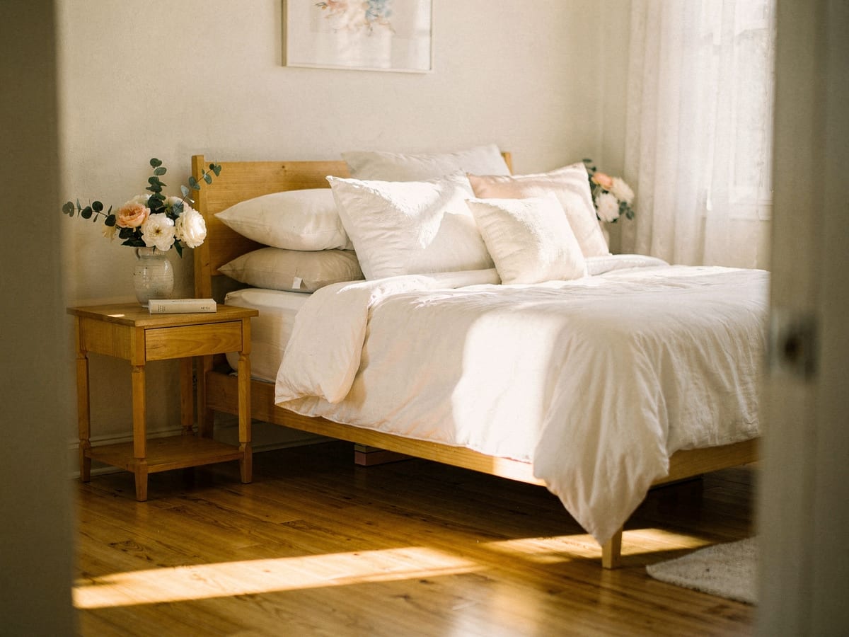 A serene, freshly made bedroom with crisp linens and fresh flowers in soft morning light