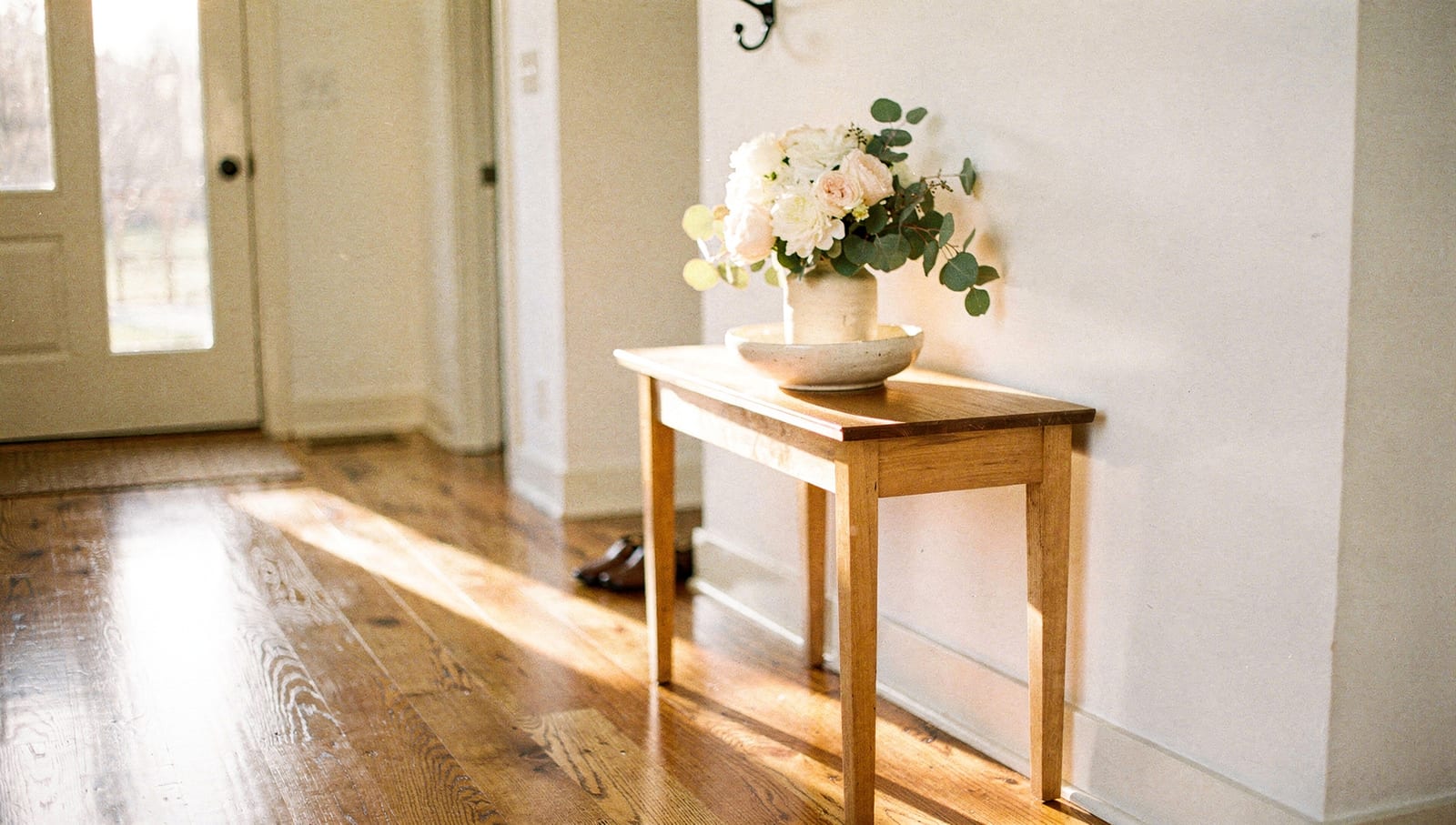 A welcoming, sunlit entryway just inside a home's front door with fresh flowers